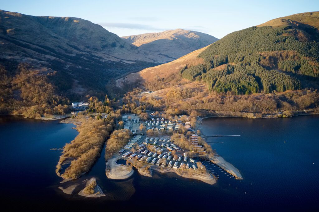 Caravan site island park at lake water edge aerial view